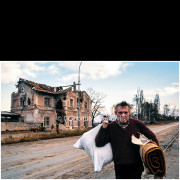 Vukovar (Croatia) – November 1991

A civilian carries personal belongings along a damaged road in Vukovar, passing a heavily destroyed building following months of shelling and street fighting.
The ruined structure and debris-lined street reflect the extensive destruction of the town during the final phase of the siege.

The photograph documents the movement of civilians through the post-combat urban landscape.
