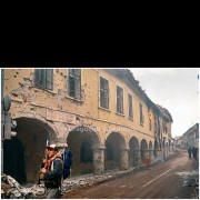 Vukovar (Croatia) – November 1991

A Serb fighter walks along a heavily damaged street in Vukovar, passing arcaded buildings scarred by shelling and small-arms fire.
The remains of urban infrastructure and ongoing fires inside the buildings reflect the intensity of combat during the final days of the siege.

The photograph documents armed movement through the devastated historic center of the town.