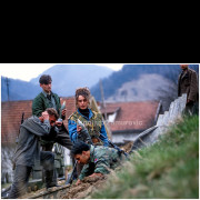 This photograph portrays Branka Mitrović, a young woman who joined the fighting around Srebrenica during the war in Bosnia and Herzegovina. The image was sent to the French photo agency Gamma, where editor Didier Contant suggested developing a broader report focused on her story. According to her account, a Muslim family with many women and children had recently been captured in the area. Fighters whose own families had been massacred demanded retaliation. Branka Mitrović positioned herself in front of the family and addressed her fellow combatants, stating that they could kill her, but that the civilians must not be harmed. The photograph documents both the presence of women in combat roles and the moral tensions faced on the front line.