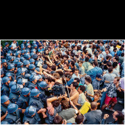 The Student Protest of 1992 began in Belgrade in mid-June as a response to the political and social crisis in Serbia. Students of the University of Belgrade, led by the Student Union of the Faculty of Electrical Engineering, initiated demonstrations that quickly spread and gained support from students across Serbia. The protest became one of the most visible expressions of dissatisfaction among young people at the time.
During the protest, students articulated demands for democratization, free media, and fair electoral conditions. Most protest activities took place within university premises and their immediate surroundings, with the main gathering point located in front of the Faculty of Philosophy. Students from art academies organized public performances and visual interventions, while Radio Index began broadcasting as the voice of the student movement.
In the early phase of the protests, police presence was limited and largely non-violent. However, when demonstrators attempted to march toward the Dedinje district, police forces were suddenly reinforced, leading to physical confrontations between the police and protesters. This photograph captures that moment — a dense police cordon facing students and citizens amid tension and disorder. The scene remains one of the defining images of the 1992 Student Protest.